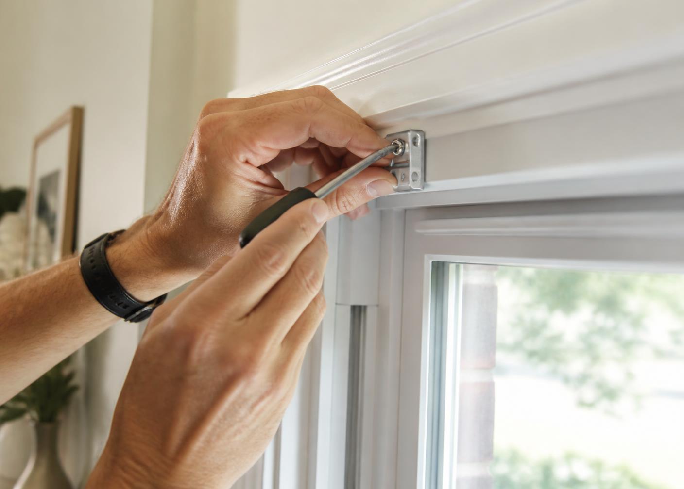 Installer fitting a blind headrail bracket to a window frame